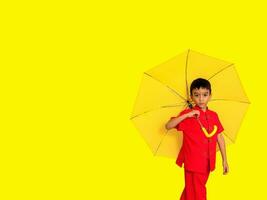 boy fashion a Chinese-style shirt holding a yellow umbrella poses for a photo shoot.