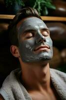 Handsome man with clay facial mask in beauty spa photo