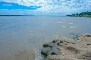 Brown rock rapids beside the big river There are clouds in the sky during the day. photo