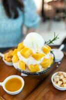 Shaved ice dessert with mango slices. Served with vanilla ice cream and whipped cream. Sweet dessert in Korean style. Local name, Bingsu. photo