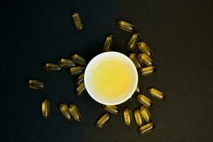 Fish oil in clear yellow capsules. for dietary supplement isolate black background photo