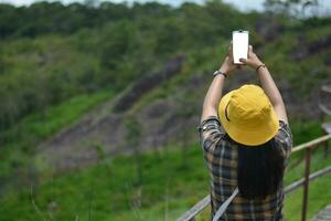 Woman standing with her back using her phone to take a picture of the front view white camera screen photo