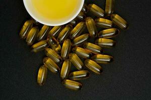 Fish oil in clear yellow capsules. for dietary supplement isolate black background photo