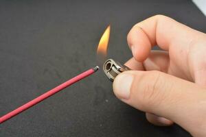 Incense stick being lit with a flame from a lighter photo