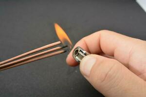 Incense stick being lit with a flame from a lighter photo