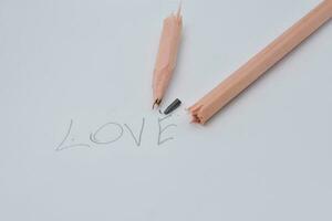 Broken pencil. Writing with a pencil the word love. White background. photo