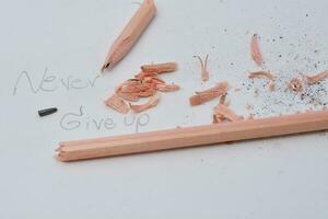 Broken pencil. Writing with a pencil the word nerver give up. White background photo