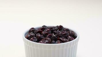 Closeup Superfood Heap Of Dried Cranberries In White Bowl On Beige Background. Selective Focus. Sweet Dehydrated Cranberries. Nutrients And Vitamins. Horizontal Plane. photo