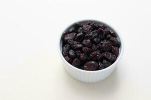 Superfood Heap Of Dried Cranberries In White Bowl On Beige Background. Selective Focus. Sweet Dehydrated Cranberries. Nutrients And Vitamins. Horizontal And Copy Space. photo