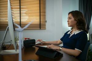Futuristic women Engineer working with Holographic Augmented Reality and 3D Wind Turbine Model on tablet at home office ,Concept of technology and environment photo