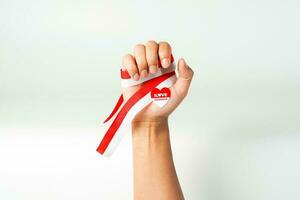 hand holding ribbon, red and white flag of Indonesia independence day August 17th, i love indonesia, isolated on white background. photo