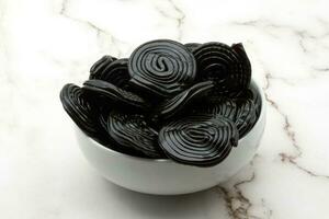 Tasty black licorice candies on white marble background photo