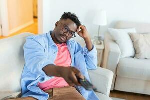 Excited African American Man Pointing Television Controller To Camera Switching Channels Watching TV . Television Programming Advertisement. Selective Focus photo