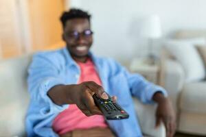 Excited African American Man Pointing Television Controller To Camera Switching Channels Watching TV . Television Programming Advertisement. Selective Focus photo