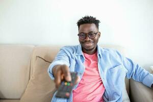 Excited African American Man Pointing Television Controller To Camera Switching Channels Watching TV . Television Programming Advertisement. Selective Focus photo