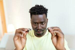 African man in glasses rubs his eyes, suffering from tired eyes, ocular diseases concept photo