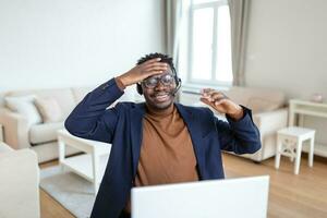 emocionado birracial masculino llamada centrar agente en auriculares tener divertido risa trabajando en computadora en línea, lleno de alegría africano americano hombre ocupado estudiando o acecho gracioso formación seminario web en computadora artilugio foto