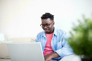 Young and determined black student studying at night at home, with a help of a laptop computer, and having a internet call. photo