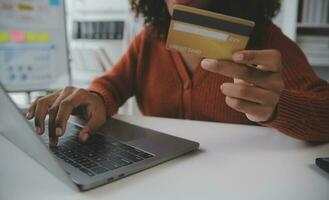 cerrar las manos femeninas con tarjeta de crédito y teléfono inteligente, mujer joven pagando en línea, usando el servicio bancario, ingresando información, comprando, ordenando en la tienda de Internet, haciendo pagos seguros foto