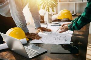 reunión de trabajo en equipo de ingenieros, trabajo de dibujo en la reunión de planos para el trabajo del proyecto con un socio en la construcción de modelos y herramientas de ingeniería en el concepto de sitio de trabajo, construcción y estructura. foto