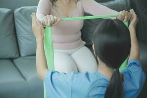 young asian physical therapist working with senior woman on walking with a walker photo