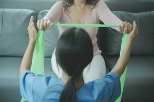 young asian physical therapist working with senior woman on walking with a walker photo