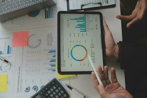 Financial analysts analyze business financial reports on a digital tablet planning investment project during a discussion at a meeting of corporate showing the results of their successful teamwork. photo