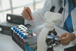 Professional lab. Amazing longhaired medical worker wearing uniform while using microscope during research photo