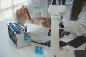 profesional laboratorio. increíble de pelo largo médico trabajador vistiendo uniforme mientras utilizando microscopio durante investigación foto