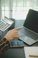 Close up Business woman using calculator and laptop for do math finance on wooden desk, tax, accounting, statistics and analytical research concept photo