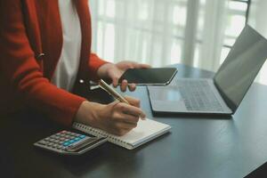 Asian Business woman using calculator and laptop for doing math finance on an office desk, tax, report, accounting, statistics, and analytical research concept photo