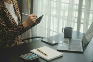 Asian Business woman using calculator and laptop for doing math finance on an office desk, tax, report, accounting, statistics, and analytical research concept photo