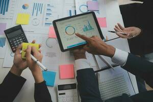 Financial analysts analyze business financial reports on a digital tablet planning investment project during a discussion at a meeting of corporate showing the results of their successful teamwork. photo