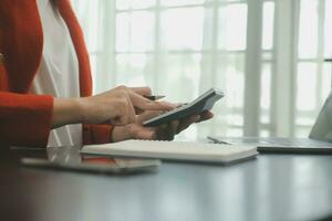 Asian Business woman using calculator and laptop for doing math finance on an office desk, tax, report, accounting, statistics, and analytical research concept photo