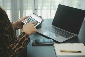 Asian Business woman using calculator and laptop for doing math finance on an office desk, tax, report, accounting, statistics, and analytical research concept photo