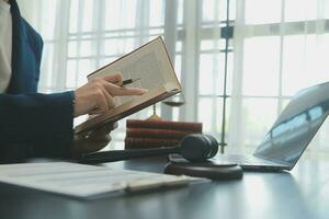 Justice and Law concept. Legal counsel presents to the client a signed contract with gavel and legal law or legal having team meeting at law firm in background photo