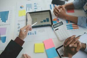 Financial analysts analyze business financial reports on a digital tablet planning investment project during a discussion at a meeting of corporate showing the results of their successful teamwork. photo