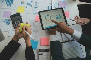 Financial analysts analyze business financial reports on a digital tablet planning investment project during a discussion at a meeting of corporate showing the results of their successful teamwork. photo