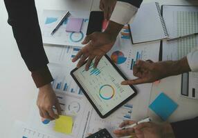 Financial analysts analyze business financial reports on a digital tablet planning investment project during a discussion at a meeting of corporate showing the results of their successful teamwork. photo