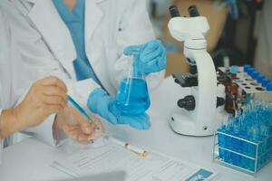 Health care researchers working in life science laboratory. Young female research scientist and senior male supervisor preparing and analyzing microscope slides in research lab. photo