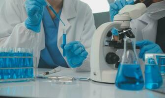 Health care researchers working in life science laboratory. Young female research scientist and senior male supervisor preparing and analyzing microscope slides in research lab. photo