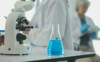 investigadores de atención médica que trabajan en el laboratorio de ciencias de la vida. joven científica investigadora y supervisora masculina senior preparando y analizando portaobjetos de microscopio en el laboratorio de investigación. foto