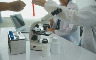 Health care researchers working in life science laboratory. Young female research scientist and senior male supervisor preparing and analyzing microscope slides in research lab. photo