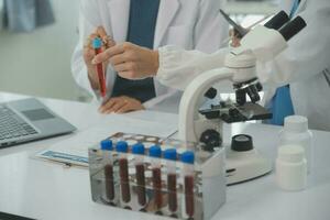 Health care researchers working in life science laboratory. Young female research scientist and senior male supervisor preparing and analyzing microscope slides in research lab. photo