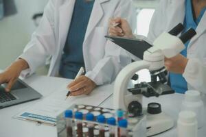 Health care researchers working in life science laboratory. Young female research scientist and senior male supervisor preparing and analyzing microscope slides in research lab. photo
