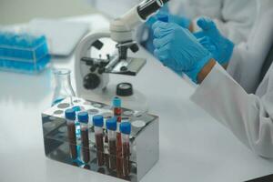 investigadores de atención médica que trabajan en el laboratorio de ciencias de la vida. joven científica investigadora y supervisora masculina senior preparando y analizando portaobjetos de microscopio en el laboratorio de investigación. foto