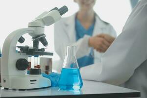 investigadores de atención médica que trabajan en el laboratorio de ciencias de la vida. joven científica investigadora y supervisora masculina senior preparando y analizando portaobjetos de microscopio en el laboratorio de investigación. foto