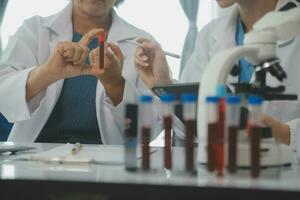 Health care researchers working in life science laboratory. Young female research scientist and senior male supervisor preparing and analyzing microscope slides in research lab. photo