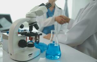 investigadores de atención médica que trabajan en el laboratorio de ciencias de la vida. joven científica investigadora y supervisora masculina senior preparando y analizando portaobjetos de microscopio en el laboratorio de investigación. foto