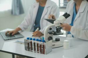 Health care researchers working in life science laboratory. Young female research scientist and senior male supervisor preparing and analyzing microscope slides in research lab. photo